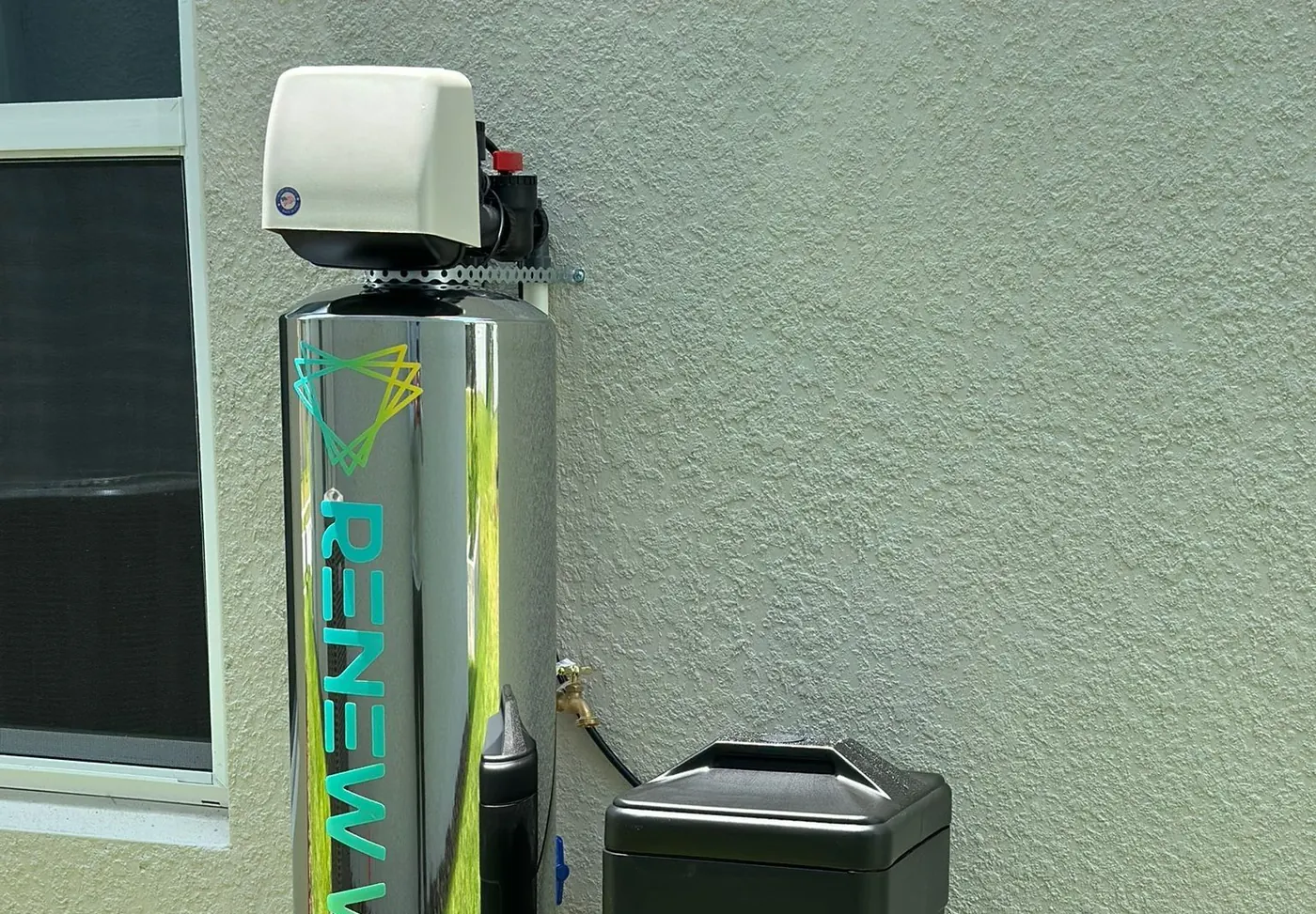 Sistema Renew Water de acero inoxidable instalado en la pared exterior de una casa